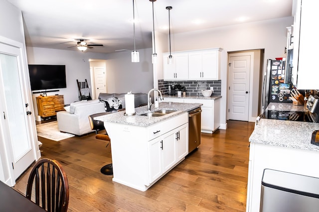 kitchen featuring pendant lighting, sink, white cabinets, and a center island with sink