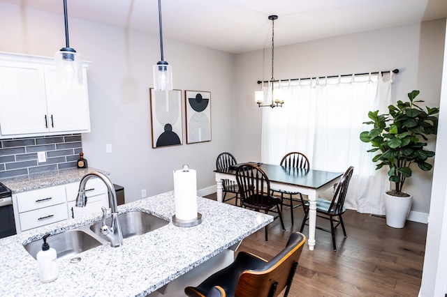 kitchen with pendant lighting, sink, a kitchen breakfast bar, and white cabinets