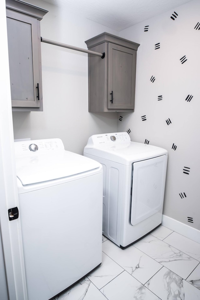 clothes washing area featuring washing machine and dryer and cabinets