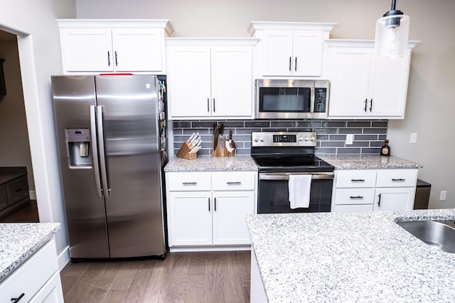 kitchen featuring white cabinetry, tasteful backsplash, stainless steel appliances, and hanging light fixtures