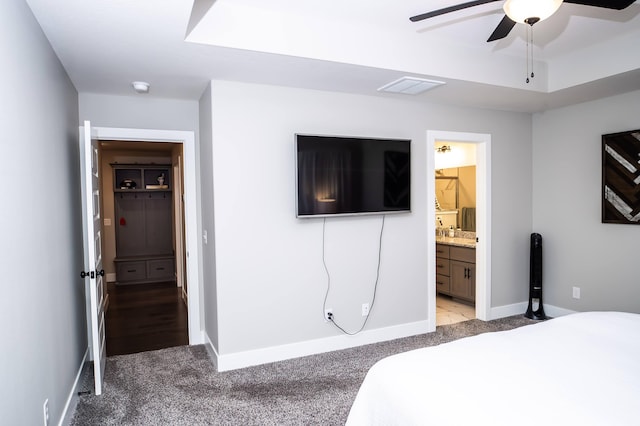 carpeted bedroom featuring ensuite bath and a tray ceiling