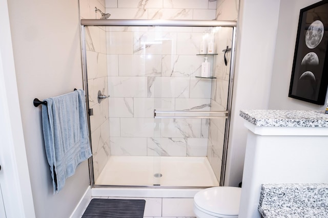 bathroom featuring a shower with door and toilet