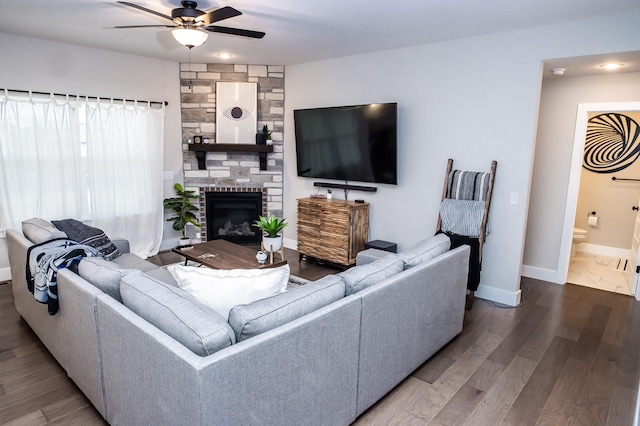 living room with hardwood / wood-style flooring, a stone fireplace, and ceiling fan