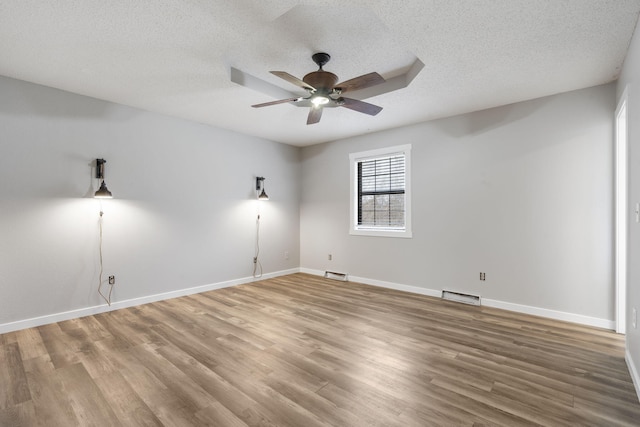 empty room with ceiling fan, hardwood / wood-style floors, and a textured ceiling