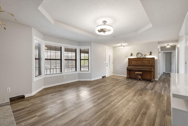 interior space with hardwood / wood-style floors, a raised ceiling, and a textured ceiling