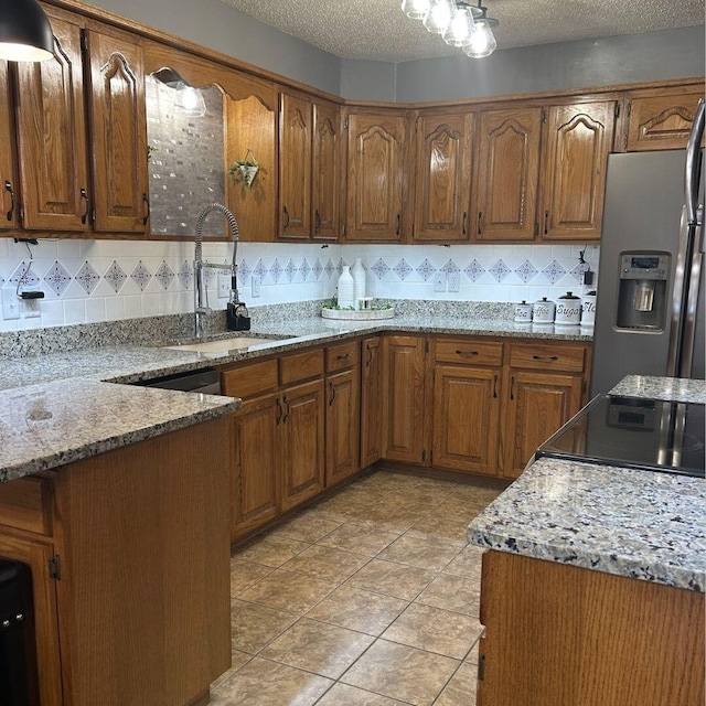 kitchen with light stone countertops, sink, a textured ceiling, and stainless steel fridge with ice dispenser