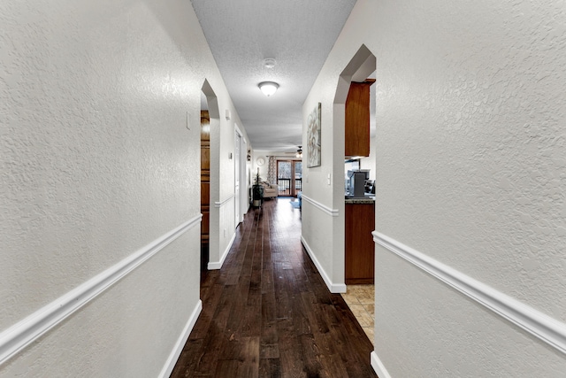 hallway with a textured ceiling and wood-type flooring