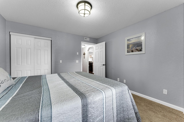 carpeted bedroom with a textured ceiling and a closet