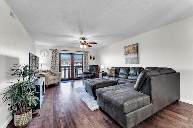 living room with a textured ceiling, ceiling fan, and dark hardwood / wood-style floors