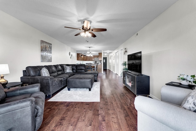 living room with dark hardwood / wood-style flooring, a textured ceiling, and ceiling fan with notable chandelier