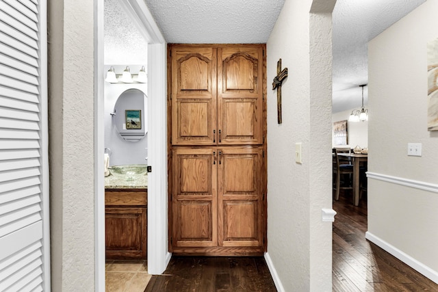 hall with a textured ceiling, dark wood-type flooring, and sink