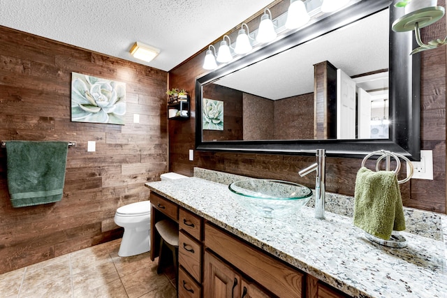 bathroom with vanity, tile patterned flooring, a textured ceiling, and wooden walls