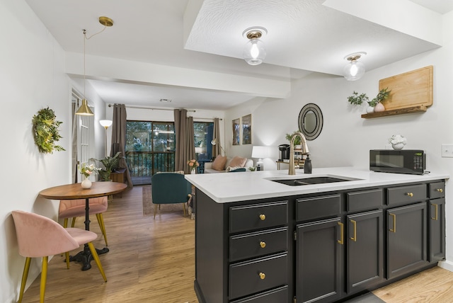 kitchen featuring light hardwood / wood-style floors, kitchen peninsula, and sink