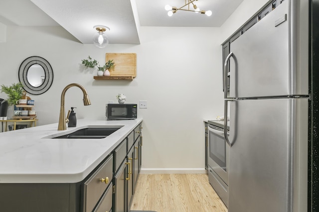 kitchen featuring kitchen peninsula, sink, light stone counters, light hardwood / wood-style floors, and stainless steel appliances