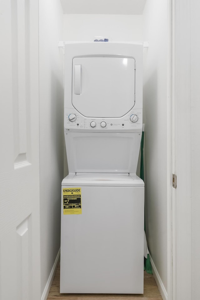 laundry room with stacked washer / drying machine and light hardwood / wood-style flooring