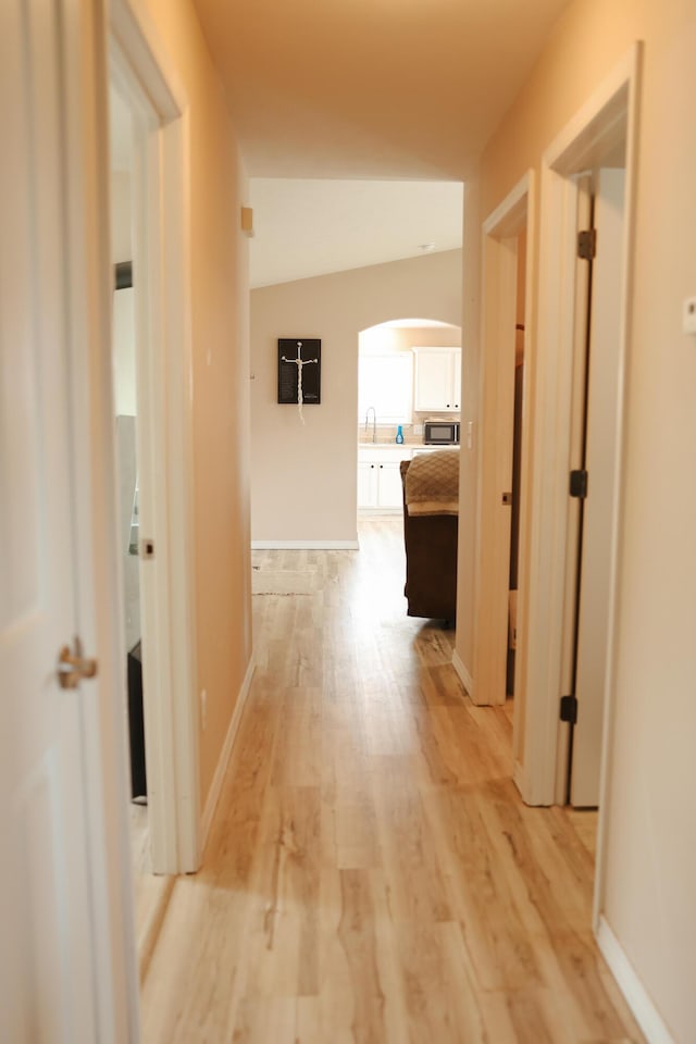 1610 Jon St, West Plains, MO 65775 - hallway with arched walkways, a sink, light wood-style floors, and baseboards