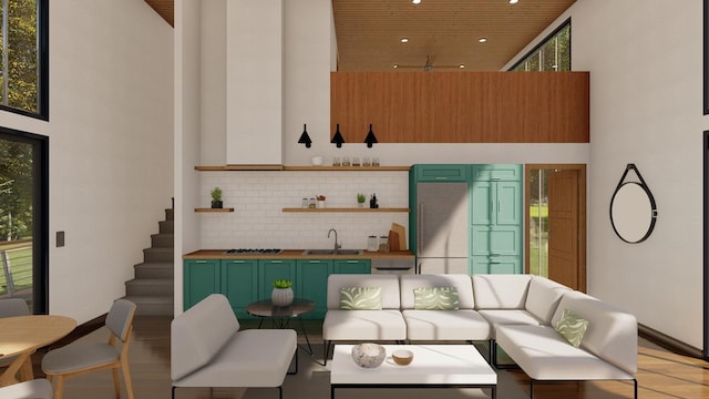 living room featuring a high ceiling, sink, and light wood-type flooring