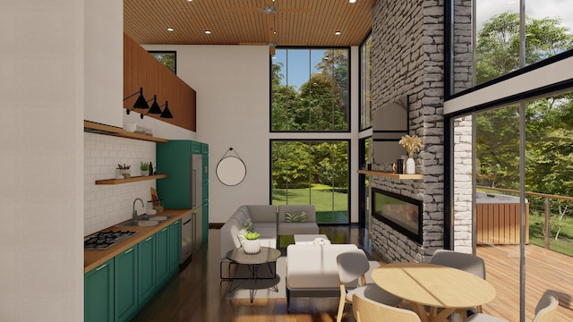 interior space featuring sink, a wall of windows, a towering ceiling, a fireplace, and light wood-type flooring