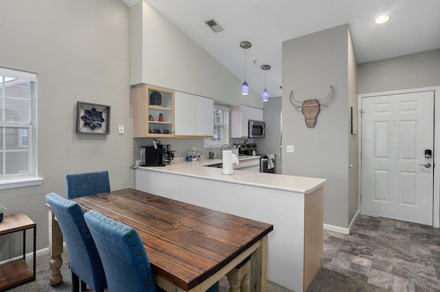 kitchen featuring pendant lighting, white cabinetry, high vaulted ceiling, stainless steel appliances, and kitchen peninsula