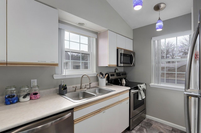 kitchen featuring lofted ceiling, sink, hanging light fixtures, stainless steel appliances, and white cabinets