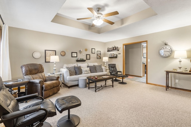 living room featuring ceiling fan, light colored carpet, and a tray ceiling