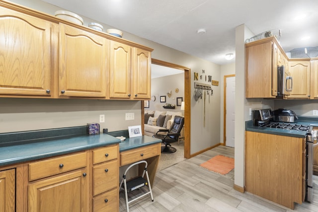 kitchen featuring built in desk, stainless steel appliances, and light wood-type flooring