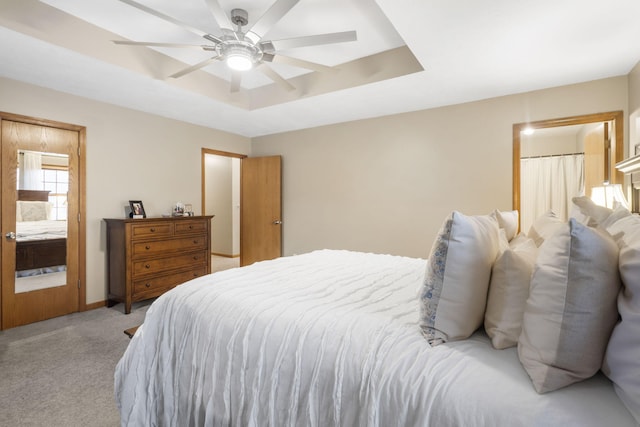 bedroom with ceiling fan, a raised ceiling, and light carpet