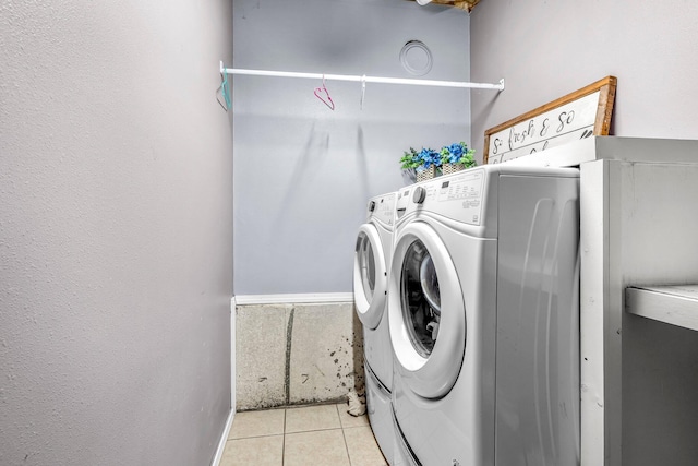 clothes washing area featuring light tile patterned floors and washing machine and clothes dryer