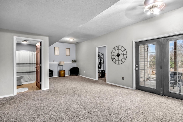 unfurnished bedroom with ensuite bath, a spacious closet, a textured ceiling, access to outside, and light colored carpet