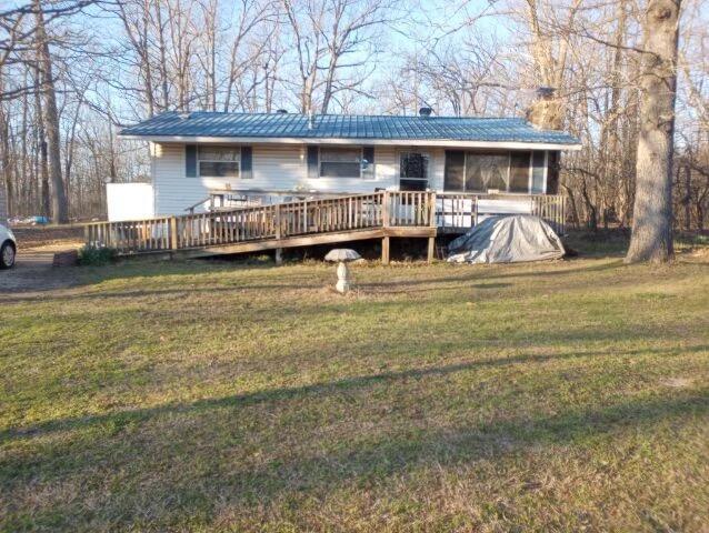 ranch-style home with a wooden deck, a sunroom, and a front lawn