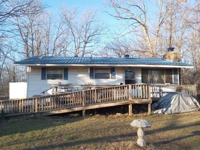 rear view of property with a wooden deck, a yard, and a sunroom