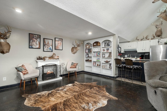 living room with a multi sided fireplace, sink, and a textured ceiling