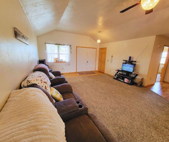 carpeted living room with ceiling fan, lofted ceiling, and a textured ceiling