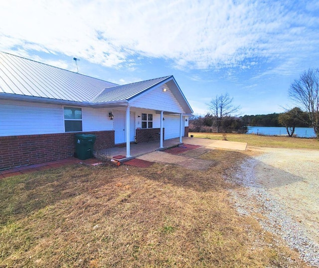 exterior space featuring a garage, a lawn, and a water view