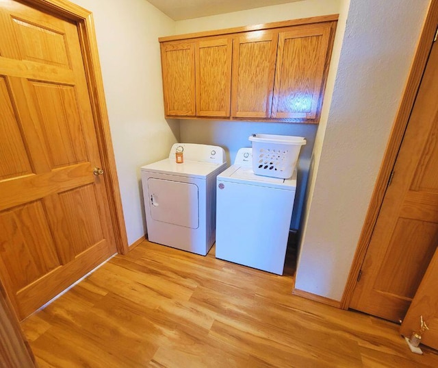 washroom featuring light hardwood / wood-style floors, cabinets, and washing machine and clothes dryer