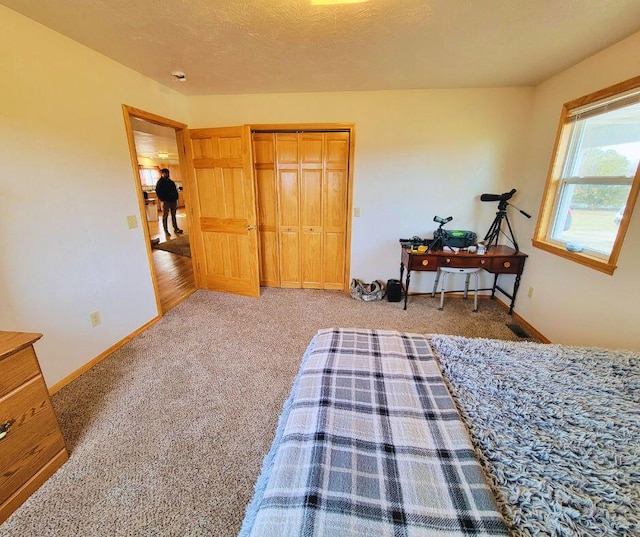 carpeted bedroom featuring a textured ceiling and a closet