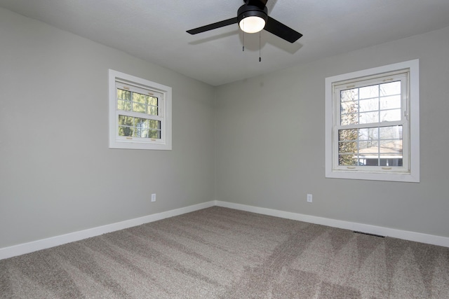 empty room featuring carpet floors, baseboards, ceiling fan, and visible vents