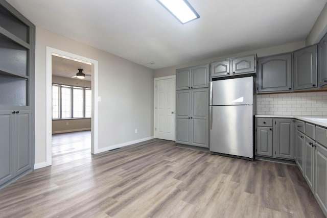 kitchen featuring light wood-type flooring, freestanding refrigerator, gray cabinetry, and a ceiling fan