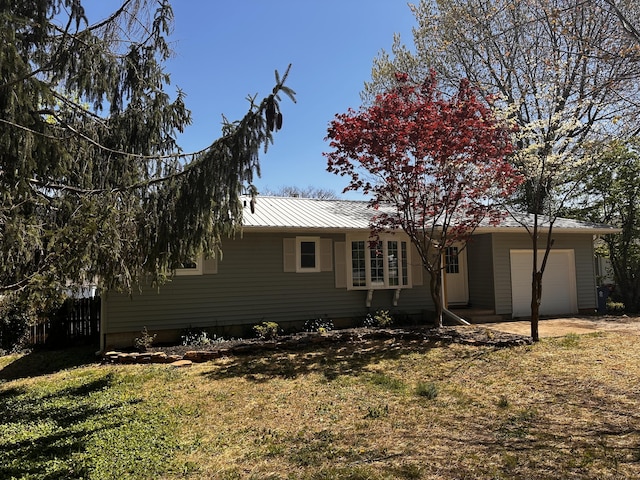 back of property with a yard, metal roof, and an attached garage