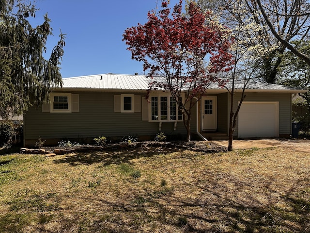 single story home featuring an attached garage, metal roof, and driveway