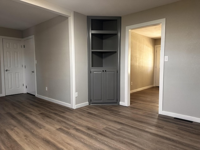 unfurnished bedroom with visible vents, baseboards, and dark wood finished floors