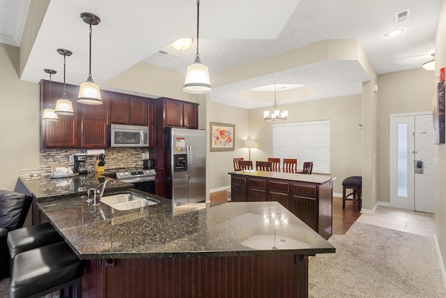 kitchen featuring a kitchen island, pendant lighting, sink, backsplash, and stainless steel appliances