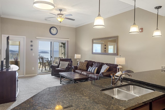 carpeted living area featuring baseboards, ornamental molding, and a sink