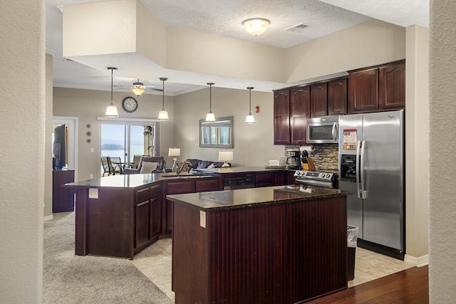 kitchen featuring visible vents, a center island, a peninsula, stainless steel appliances, and a sink