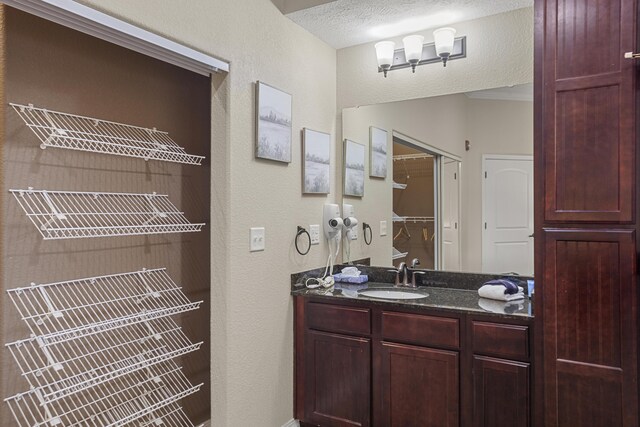 bathroom with a textured ceiling, a textured wall, and vanity