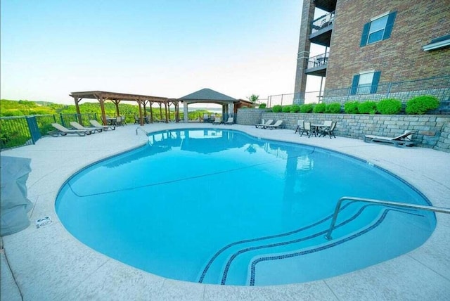 pool with fence, a gazebo, and a patio