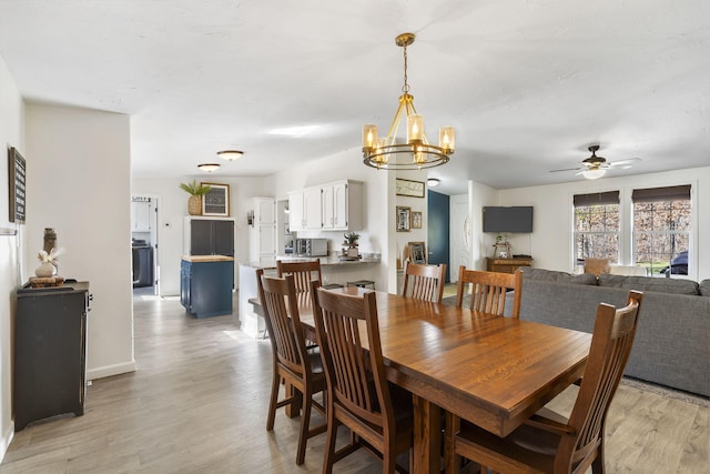 dining space featuring ceiling fan with notable chandelier and light wood-type flooring