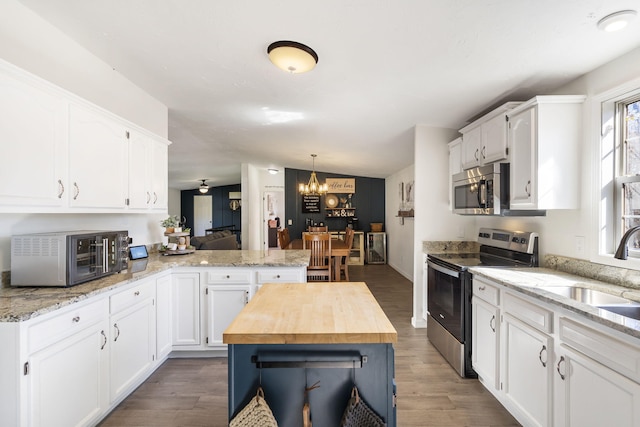 kitchen featuring white cabinetry, wood counters, stainless steel appliances, and a kitchen island