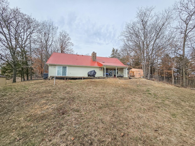 back of property with a storage shed and a lawn