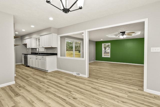 kitchen with sink, ceiling fan, a textured ceiling, white cabinets, and light wood-type flooring